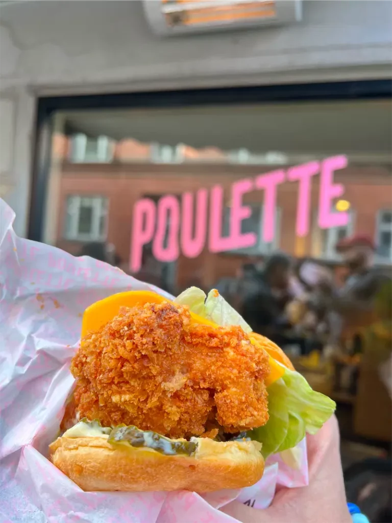 Burger z kurczakiem z Poulette na tle witryny restauracji